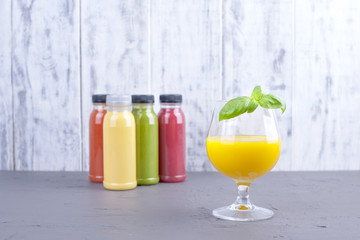 Juice in bottles, different and in a glass. Gray background. Detox food. Copy space.
