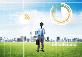 Camera headed man standing on green grass against modern cityscape
