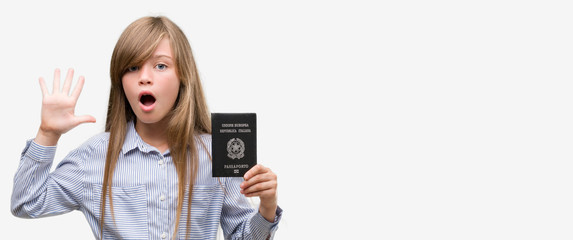 Young blonde toddler holding italian passport very happy and excited, winner expression celebrating victory screaming with big smile and raised hands