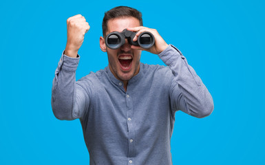 Naklejka premium Handsome young man looking through binoculars annoyed and frustrated shouting with anger, crazy and yelling with raised hand, anger concept