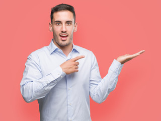 Handsome young businessman amazed and smiling to the camera while presenting with hand and pointing with finger.