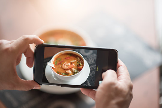 Closeup hand holding phone shooting food thai photograph in the restaurant