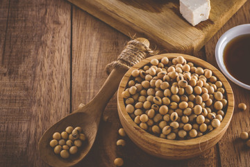 Close up of soybeans in wooden bowl. Soy products tofu and sauce, vintage tone, selective focus