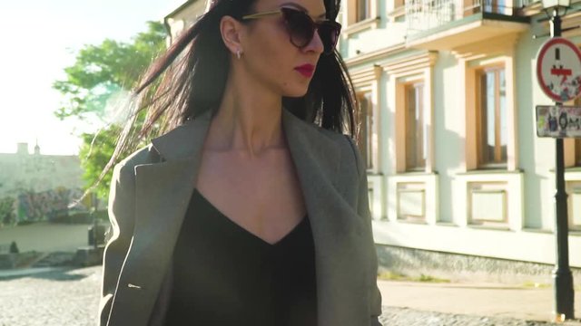 Elegance stylish woman in sunglasses walking at the street in slow motion