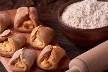 flour in clay bowl products for making cheesecakes on a wooden chopping board. Homemade Cottage cheese cookies on black background. still life composition