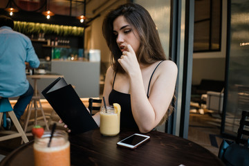 Beautiful woman looking at menu in cafe