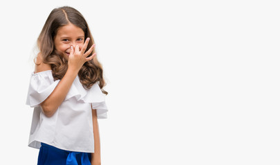 Brunette hispanic girl smelling something stinky and disgusting, intolerable smell, holding breath...