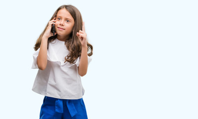 Brunette hispanic girl using smartphone surprised with an idea or question pointing finger with...