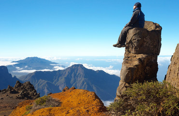 Resting man sitting on the rock above the crater Caldera de Taburiente, Island of La Palma, Canary Islands, Spain