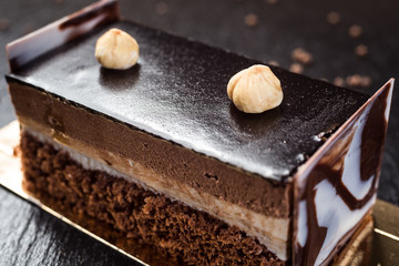 Dark chocolate vegan cake with candies and nuts on wooden background