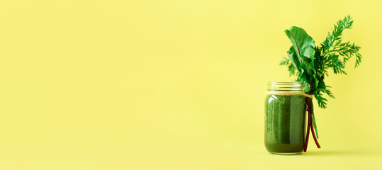 Banner of smoothie with beet greens and carrot tops on yellow background, copy space. Summer vegan food concept. Healthy detox eating, alkaline diet. Fresh juice, drink from vegetables. Leafy greens.
