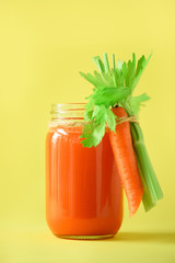 Organic carrot juice with carrots, celery on yellow background. Vegetable smothie in glass jar. Copy space. Summer food concept. Healthy detox eating, alkaline diet