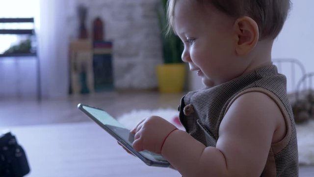 modern childhood, kid is playing with cell phone at home close-up on unfocused background