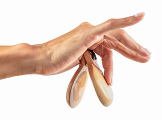 castanets in the hand of a young girl with thin graceful fingers on a white background - obrazy, fototapety, plakaty
