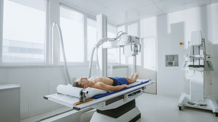 In the Hospital, Man Lying in Bed during X-Ray Machine Scanning Procedure. Scanning for Fractures,...