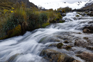 View on a cloudy day of the snowy Huaytapallana next to a small river in the central mountain range of the Peruvian Andes