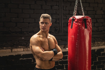 Strong young mma fighter and red punching bag
