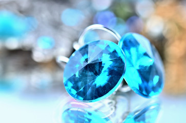 Close-up of blue earrings jewels - reflection effect - colored backgrounds