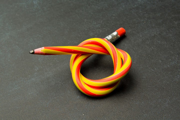 Flexible pencil on a textured cardboard background. Bent pencils two-color