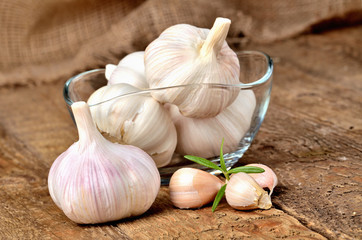 Fresh garlic in glass places on rustic wooden boards
