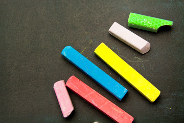 Dark chalkboard with colored crayons for drawing. Copy space
