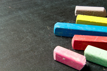 Dark chalkboard with colored crayons for drawing. Copy space