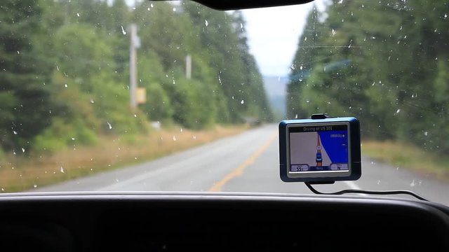 A navigational gps screen attached to the windshield of a vehicle while driving down the road.