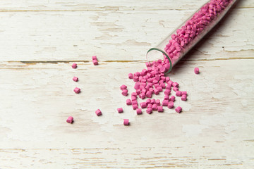 Plastic pallets . Plastic raw materials in granules for industry. Polymeric dye pink on a светлом деревянном background. Plastic granules after processing of waste polyethylene and polypropylene