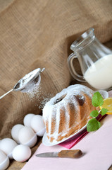 Woman sprinkles a homemade marble cake with sugar, lemon, melissa, milk, eggs and butter