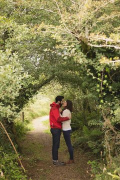 Affectionate couple kissing under tree canopy