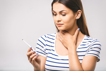 Obraz premium Portrait of a worried young beautiful woman checking her temperature. White background, flu.