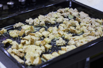 Crackers for Caesar salad. Pieces of bread on a baking sheet in garlic sauce