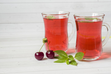 Cherry juice with mint leaves and fresh cherries on a white wooden table. Copy space
