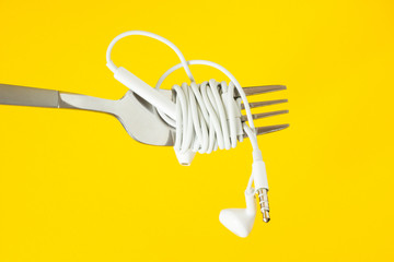White headphones and fork on a yellow background