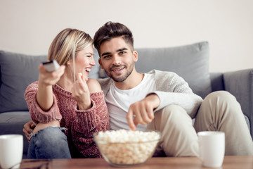 Obraz na płótnie Canvas Young couple watching tv on sofa