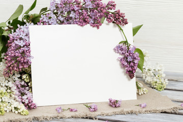 Floral background with lilac flowers and paper list for congratulations. Festive postcard. Copy space for text.