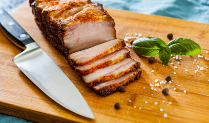 Close up view of a piece of roasted pork belly on wooden cutting board