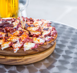 Delicious Wooden plate of galician style cooked octopus and Glass of cold beer . Pulpo a la gallega