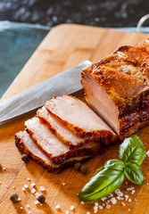 Close up view of a piece of roasted pork belly on wooden cutting board