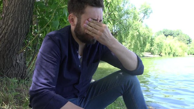 Financial difficulties stressed young casual man outdoor thinking alone in park 