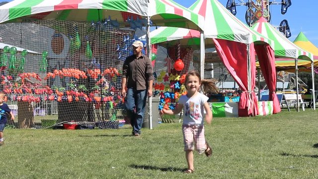 Two kids running at the county fair.