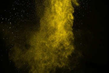 abstract yellow powder splatted on black background,Freeze motion of color powder...