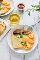 Breakfast eggs with bacon and arugula with yellow tomatoes on a wooden table
