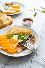Breakfast eggs with bacon and arugula with yellow tomatoes on a wooden table