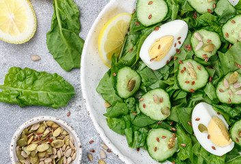 Useful spinach salad, cucumbers, eggs and seeds (pumpkin, flax and sunflower) with lemon and olive oil. Dietary food. Healthy Breakfast or dinner. Selective focus