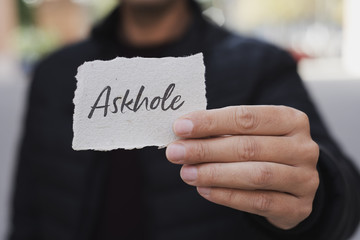 man showing a note with the word askhole in it