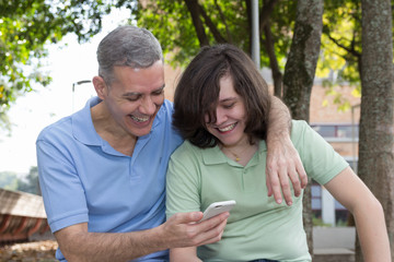 Obraz premium Dad and son. Fathers Day. Man with grey hair is holding cell phone and showing it. Concept of family, togetherness.