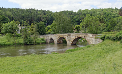 Fototapeta na wymiar Old arched stone bridge across the River Derwent at Kirkham in North Yorkshire, England