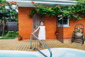 adorable little child standing at swimming pool near country house