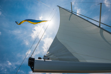 Looking up through full white sails with Ukrainian flag flying in the rigging